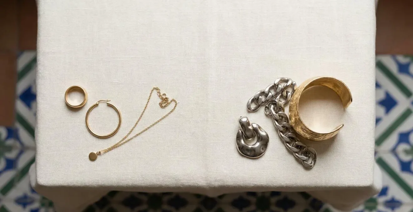 Composición editorial de joyería atemporal y tendencias efímeras sobre superficie minimalista con iluminación natural suave