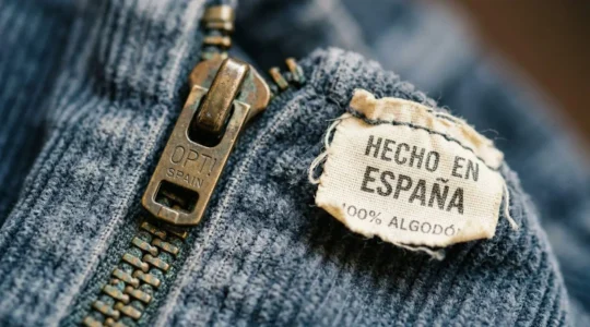 Detalle macro de cremallera metálica y etiqueta vintage de prenda española de los años 70