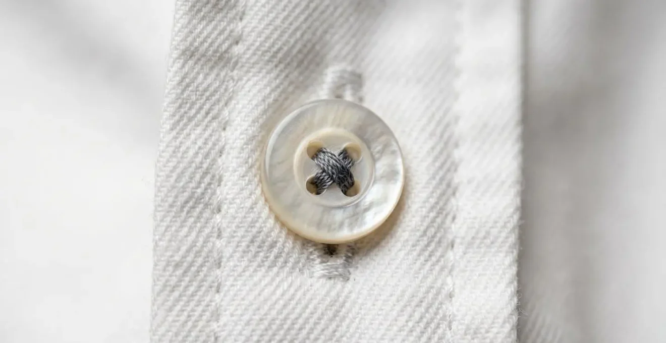 Detalle macro de costuras y botones de camisa blanca de calidad