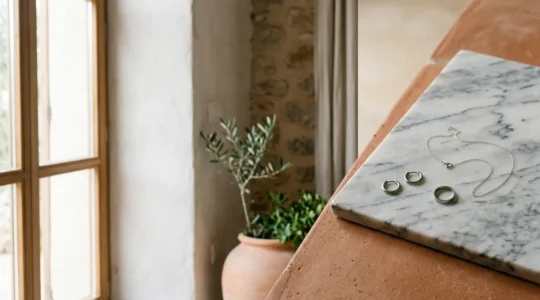 Joyas minimalistas de titanio sobre superficie neutra con luz natural suave
