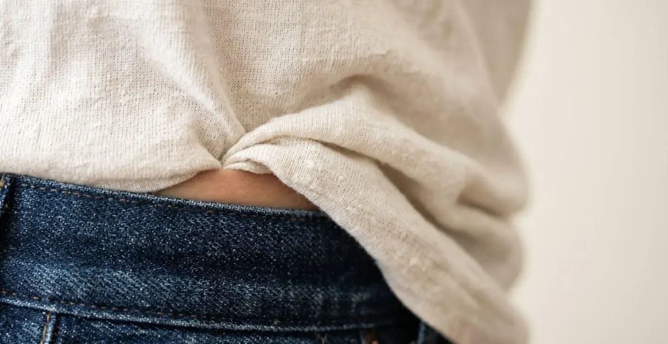 Detalle de una silueta femenina mostrando la técnica del french tuck con una camiseta metida por delante del pantalón