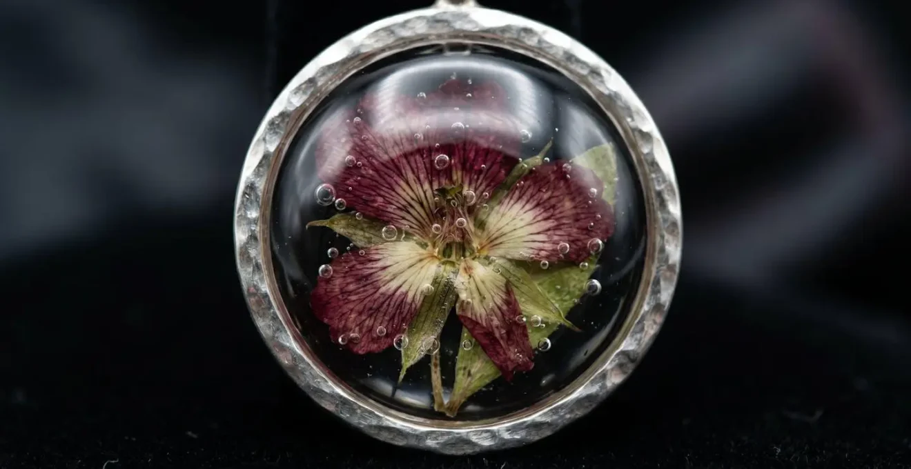 Colgante artesanal de flor preservada en resina con engarce de plata vista macro