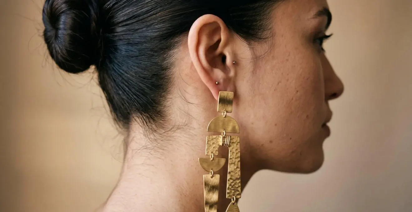 Detalle de oreja con pendientes largos y peinado recogido alto que ilustra el equilibrio visual.